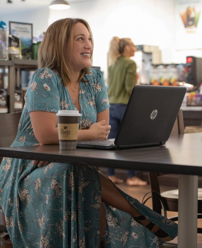 About: Easy USA Trips 4 Chattanooga Travel Blogger Kathy Brown sits at a coffee bar and laptop writing her newest travel blog post.