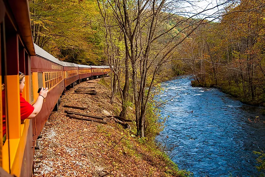 The Best Things to Do in Bryson City, NC 6 Passenger taking a photo from the Great Smoky Mountains Railroad as it winds along the Nantahala River โ one of the most popular things to do in Bryson City NC.