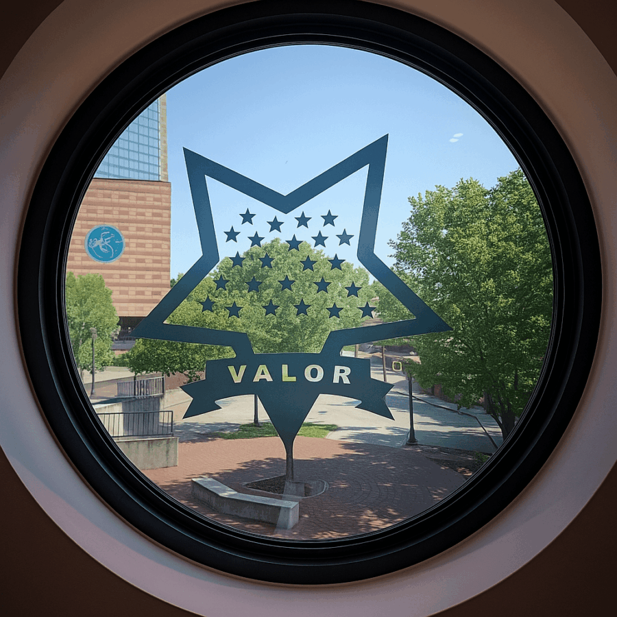 5 Powerful Reasons to Visit the Medal of Honor Museum in Chattanooga, TN 6 A circular window at the National Medal of Honor Museum Heritage Center in Chattanooga, TN, featuring the VALOR star emblem with stars etched on glass. Outside, a sunny view shows a brick plaza, trees, and the nearby aquarium building.