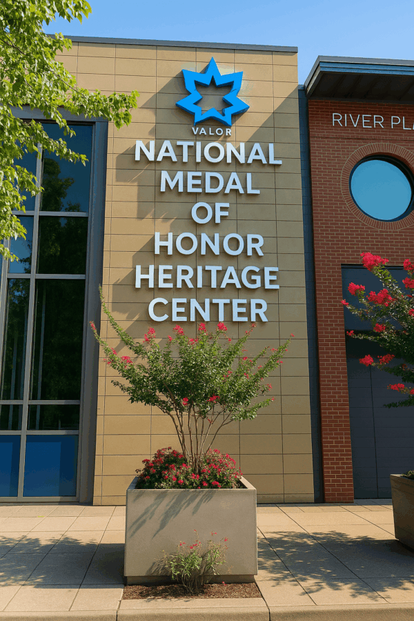 5 Powerful Reasons to Visit the Medal of Honor Museum in Chattanooga, TN 5 A bright daytime view of the National Medal of Honor Museum Heritage Center in Chattanooga, TN. The building features tan stone with bold white lettering, a blue Valor star emblem at the top, and a flowering crepe myrtle tree planted in front.