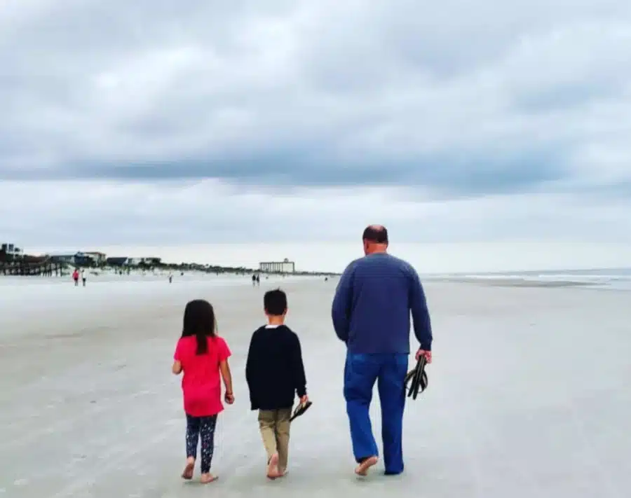 Top things to do in Neptune Beach Florida 2 Things to do in Neptune Beach Florida A man walking barefoot with two children along the wide, uncrowded shoreline of Neptune Beach, Florida under a cloudy sky.