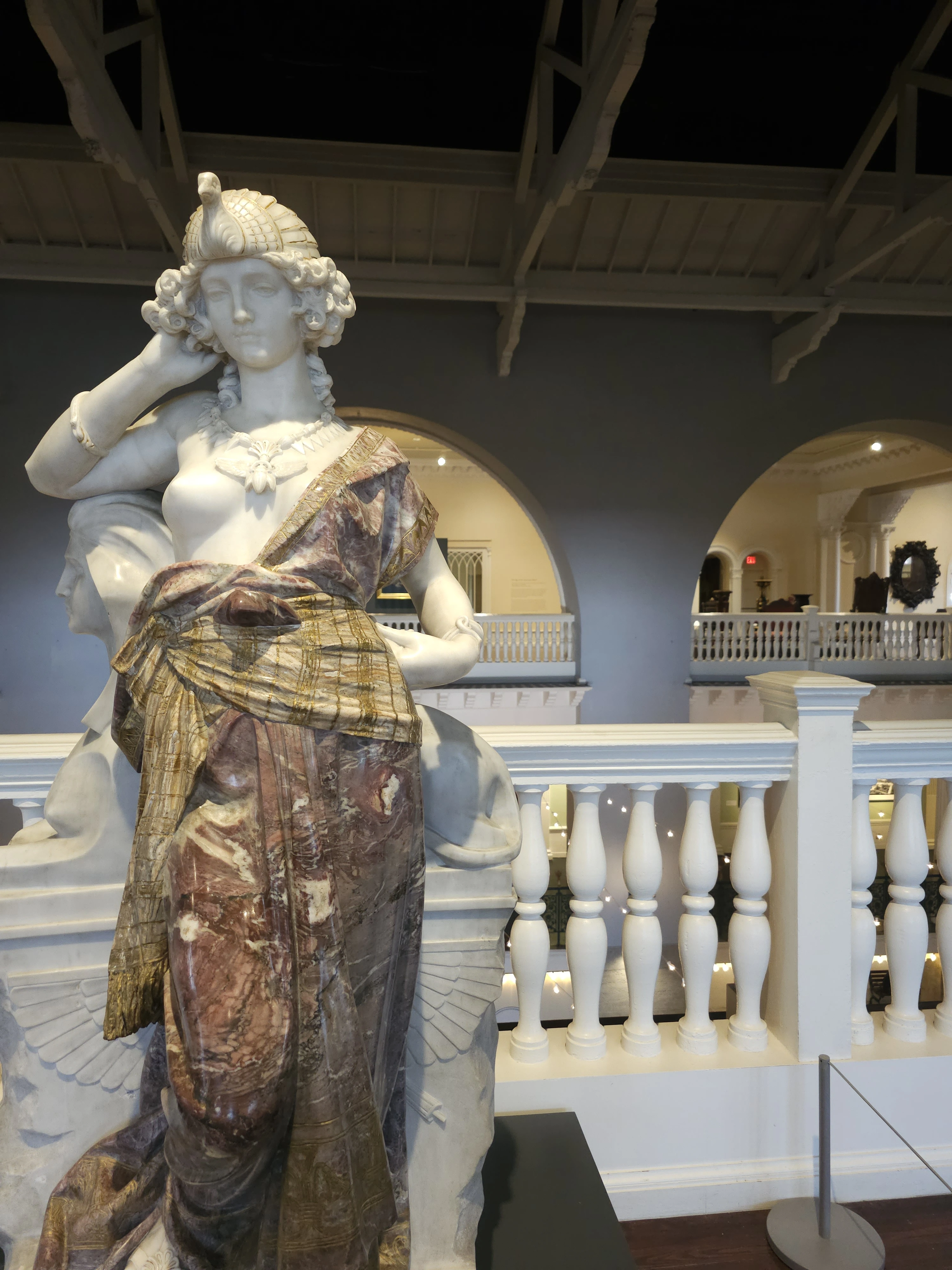 Top-Rated Favorite Things to Do St. Augustine, Florida 2 part of the collection at the Lightner Museum in St. Augustine, Florida. It features a classical-style female figure with intricate detailing, including a richly textured and colored marble garment. The figure is adorned with a decorative headdress (shaped like a bird or swan), and the sculpture’s background suggests it's displayed on the upper level of the museum, which is known for its elegant, historic interior architecture.