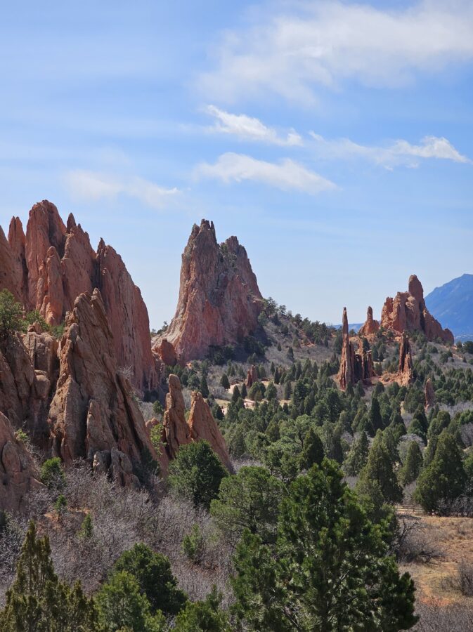 A No-Hike Way to See Garden of the Gods: Scenic Drive Tips for Older Travelers 8 Towering red sandstone spires and cliffs surrounded by evergreens at Garden of the Gods, with dramatic peaks and blue sky.