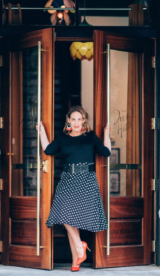 5 Star Hotels in Chattanooga, Tennessee to Book Now. 13 Kathy Brown standing confidently in the doorway of The Dwell Hotel in Chattanooga, Tennessee, wearing a black top, polka dot skirt, and red heels.
