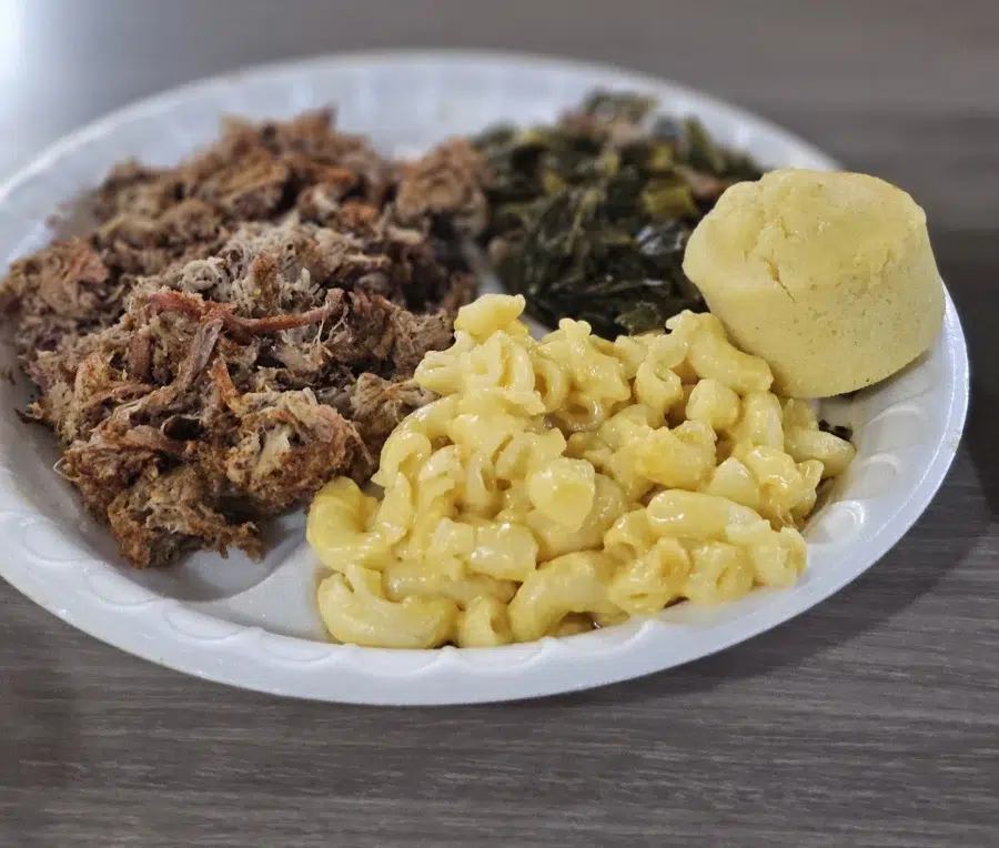 9. Fun Things to Do In Palm Coast, Florida 8 Plate of Southern-style barbecue featuring pulled pork, creamy macaroni and cheese, collard greens, and a cornbread muffin, served on a white disposable plate.