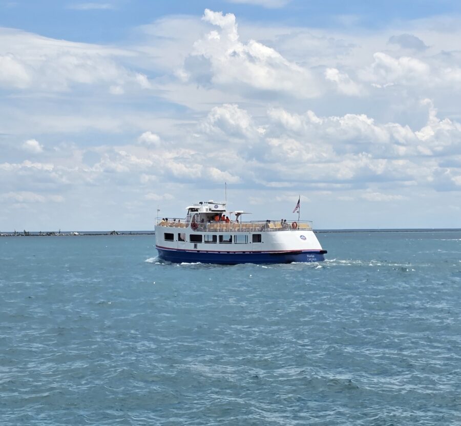 Chicago water taxi cruising across Lake Michigan on a sunny day, operated by Shoreline Sightseeing with passengers enjoying views from the upper deck.